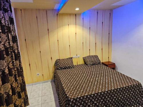 a bedroom with a bed and a wooden wall at Le Rêve d'Or in Lomé