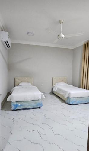 two beds in a white room with marble floors at Sahalnoot flats in Salalah