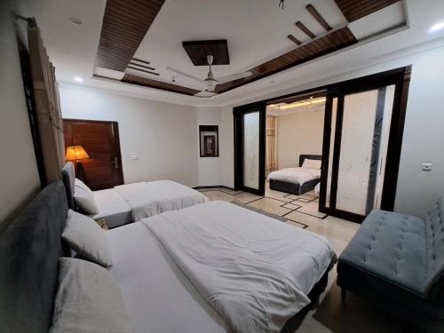 a bedroom with two beds and a couch and windows at Canvas 430 in Islamabad