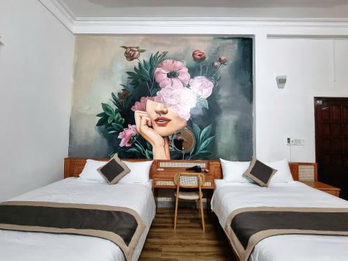 a room with two beds and a painting on the wall at Royal Homestay And Coffee in Thôn Lại Thê