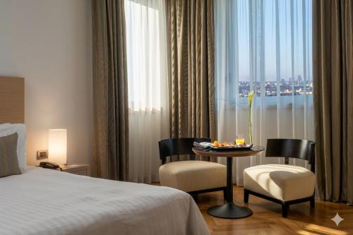 a hotel room with a bed and a table and chairs at Domina Milano Fiera in Novate Milanese