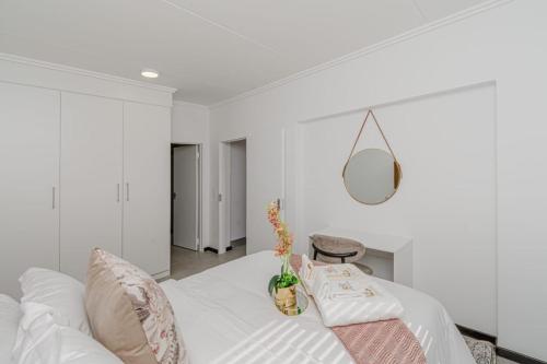 a white bedroom with a white bed with pillows at Royalty Suites in Chartwell Sandton in Chartwell