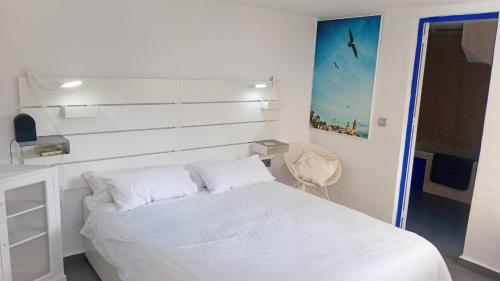 a bedroom with a white bed and a chair at El Portal, 12 mins from Sitges in Olivella