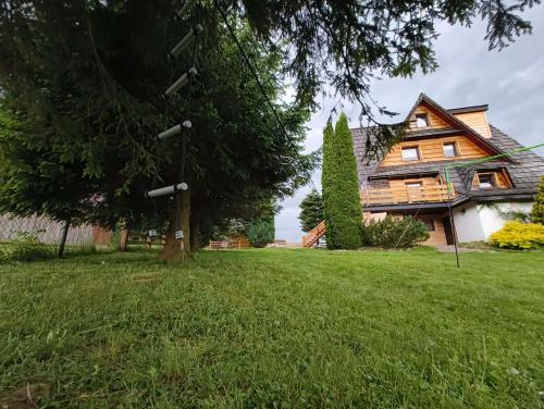 a house with a tree in the yard at Dom Górski Klimat-Willa 160 m2 z wewnętrzną sauną fińską in Zakopane