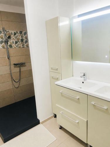 a white bathroom with a sink and a shower at Jungle Gite in Fumel