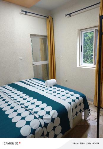 a bedroom with a bed with a blue and white blanket at or bleu in Lomé
