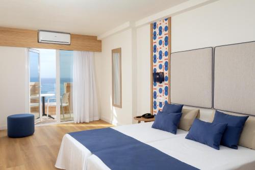 a bedroom with a large bed with blue pillows at Aparthotel Los Dragos del Sur in Puerto de Santiago