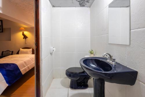 a bathroom with a sink and a toilet and a bed at SAN BLAS PLAZA INn in Cusco