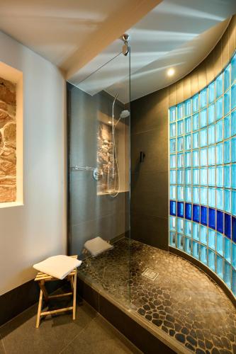 a bathroom with a glass shower with a stool at WeinHotel Fritz Walter in Niederhorbach