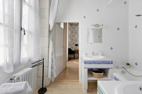 a white bathroom with a sink and a tub at Maison D'hôtes Saint-Gildas in Beaufort-en-Vallée