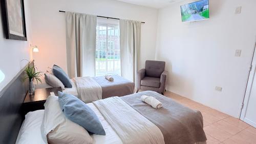 a bedroom with two beds and a chair and a window at G8 Hermoso Monoambiente con Cochera 2 huéspedes in Villa Ángela