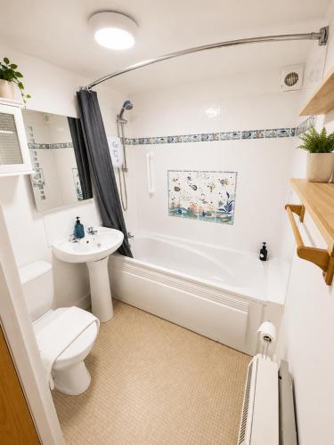 a bathroom with a tub and a toilet and a sink at Dolphin Bay Suites in Ardersier