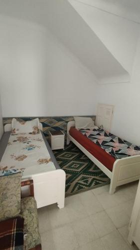 a bedroom with two beds and a rug at Maison Lyne in Hammamet