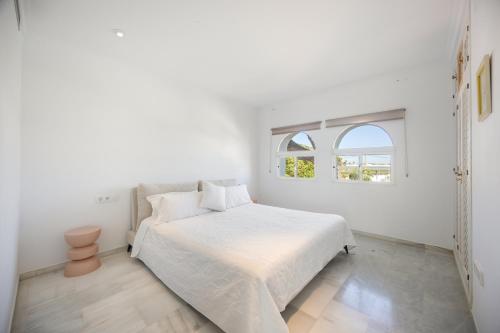 a white bedroom with a bed and a window at Finca Isla Verde in Chipiona
