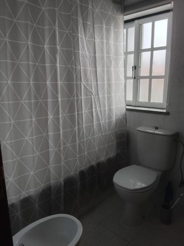 a bathroom with a toilet and a shower curtain at Garça-Real 2 in Vale de Madeiros