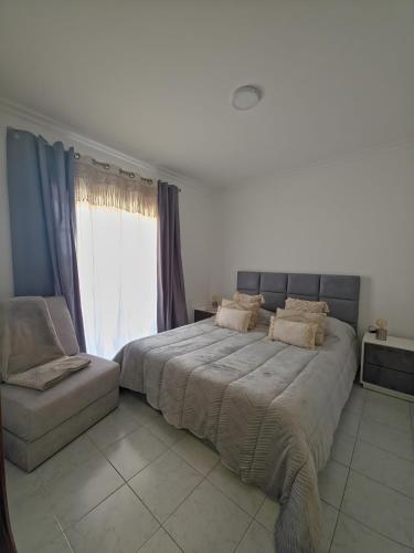 a bedroom with a large bed and a chair at Garça-Real 2 in Vale de Madeiros