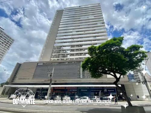 a tall building with a tree in front of it at Studio Diamante no CENTRO com piscina, academia e opção de vaga privativa in Juiz de Fora