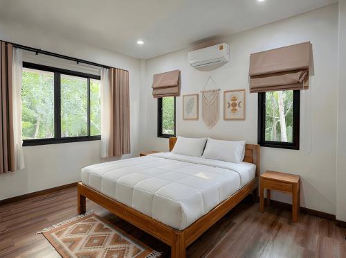 a bedroom with a bed with white sheets and windows at Soul House - Stay Beautifully in Ko Kong Nui