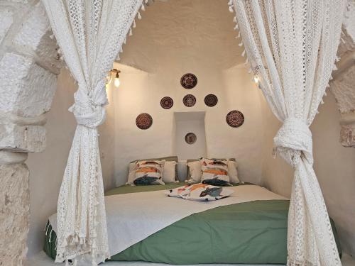 a bedroom with a bed with white curtains at Dar Chauphaly in Houmt Souk