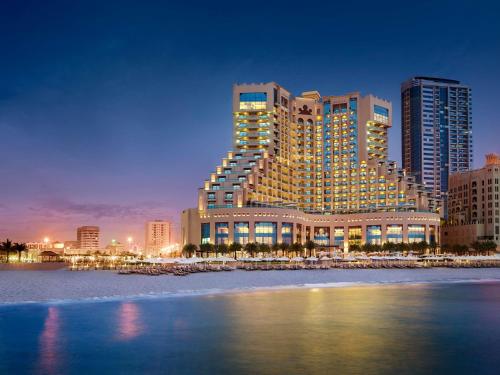 a large building on the beach in front of a city at Fairmont Ajman in Ajman 