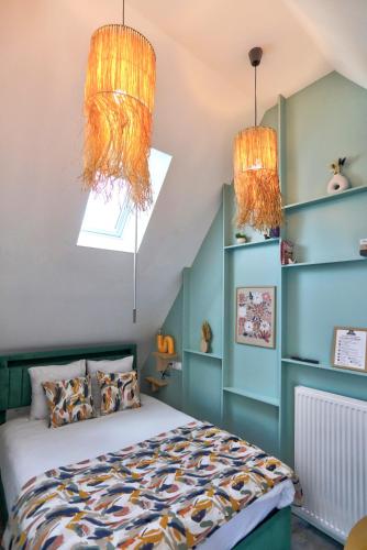a bedroom with a bed and two chandeliers at Gîte du Merlin in Plumergat
