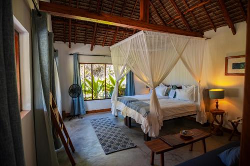 a bedroom with a bed with a mosquito net at Sava Dunes in Miramar