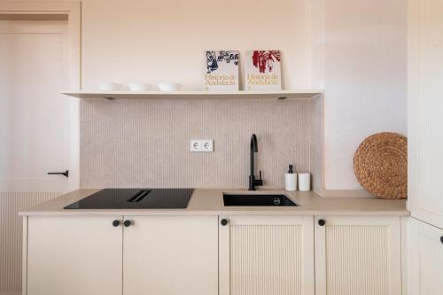 a kitchen with white cabinets and a sink at Magno Collection Palacio de Becas in Seville