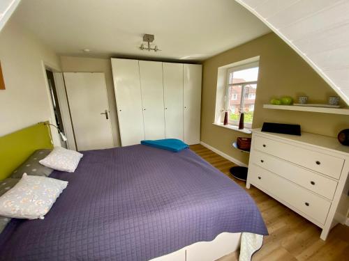 a bedroom with a purple bed and a window at HausJensen in Niebüll