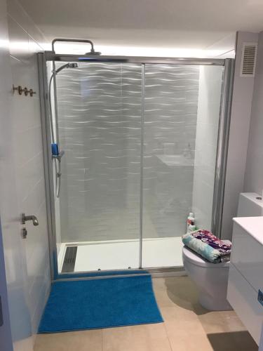 a bathroom with a shower with a toilet and a blue rug at Apartamento Adrover in Cala Millor