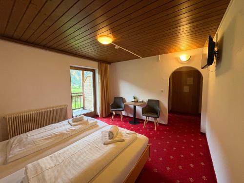 a bedroom with a bed and a table and chairs at Sidan Hotel Restaurant & Pizzeria in Schwendau