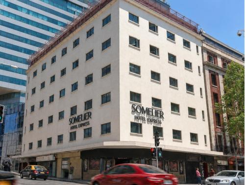 a white building on a city street with cars at Hotel Sommelier Agustinas in Santiago