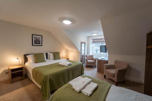a bedroom with a bed and a chair in a room at White Swan Hotel in Alnwick