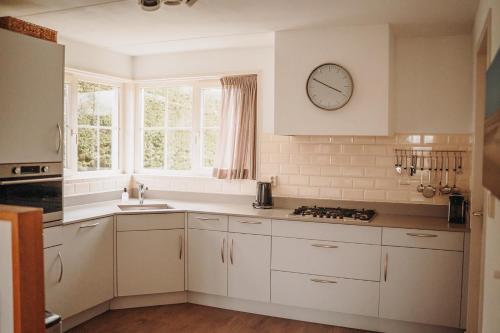 a kitchen with white cabinets and a clock on the wall at Dutchen Waddenduyn in Den Burg