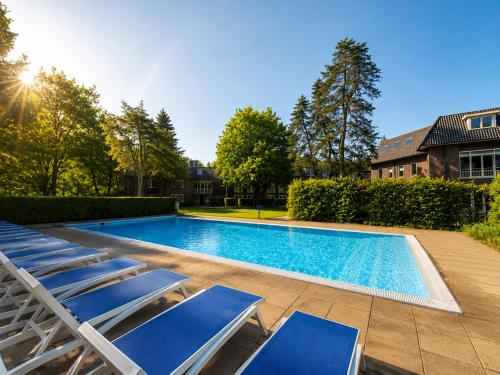 a swimming pool with lounge chairs next to a house at Hotel De Werelt Garderen in Garderen