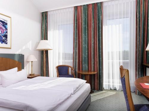 a hotel room with a bed and a desk and a window at Congress Hotel Weimar by Mercure in Weimar