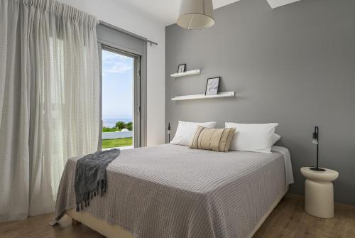 a white bedroom with a bed and a window at Nouvelle Villa in Ierapetra