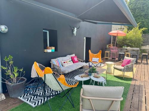 a patio with chairs and tables and an umbrella at La Villa d'ElodibiZa, 45mn de Paris en train avec piscine ! in Écuelles