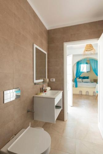 a bathroom with a sink and a toilet and a bedroom at Dar Ahlem Djerba in El Guecheïne