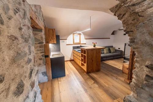 a kitchen and living room with a stone wall at Giuly's Home Luxury in Bormio