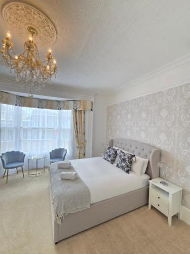 a bedroom with a large bed and a chandelier at Beaufort Lodge - Central Location & Free Parking in Taunton