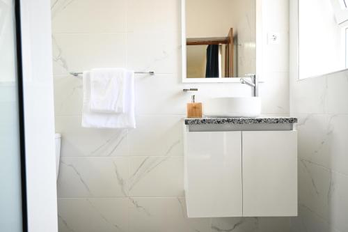 a white bathroom with a sink and a mirror at Hotel Rocha in Ribeira Grande