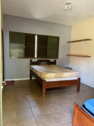 a bed in a room with a window and a table at Rancho Dias Mágicos in Uberlândia