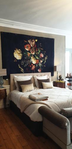 a large bed with a large painting on the wall at Des fleurs au balcon in Quintin