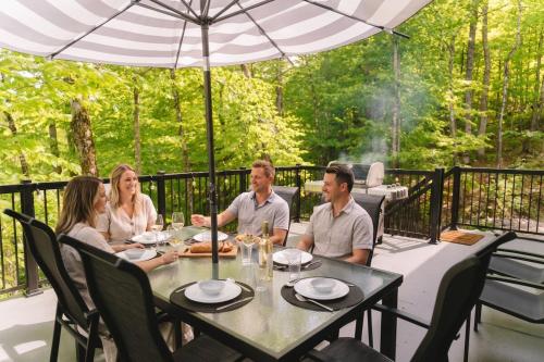 a group of people sitting around a table on a patio at Java with Private Spa & Games, Lake & Golf in Saint-Raymond