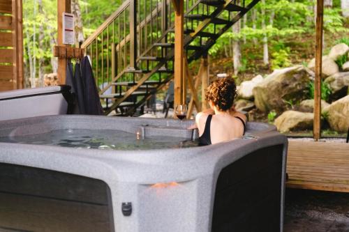 a woman sitting in a jacuzzi tub with a fire at Java with Private Spa & Games, Lake & Golf in Saint-Raymond