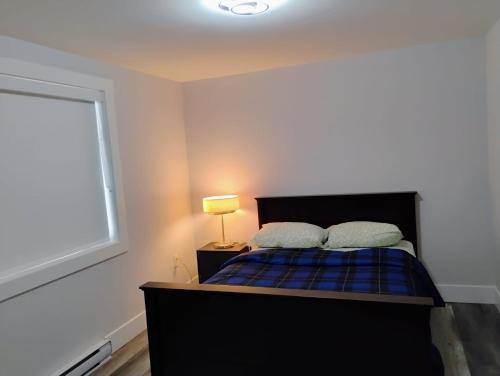 a bedroom with a bed and a window and a lamp at Apartment in Fredericton in Fredericton