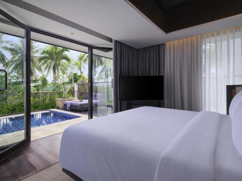 a bedroom with a bed and a swimming pool at Pullman Lombok Merujani Mandalika Beach Resort in Kuta Lombok