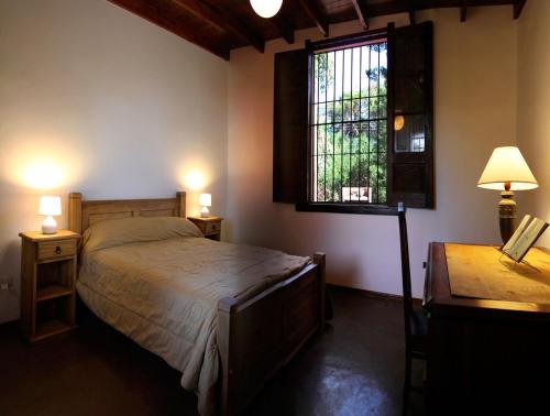 a bedroom with a bed and a window and a desk at Cabañas Estancia Balumba in Capilla del Monte