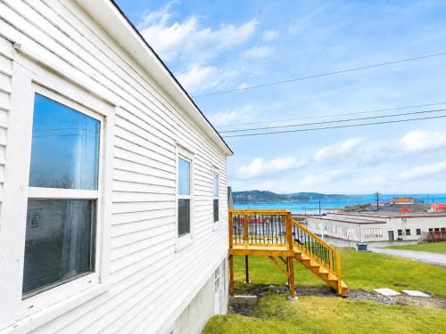 a porch of a white house with a large window at Gus & Nellie's Place in Twillingate