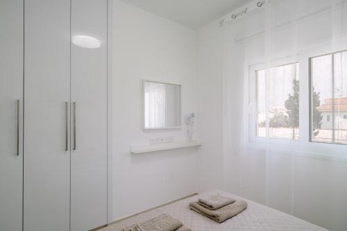 a white bathroom with a shower and two towels at Myrtiana 10 in Oroklini
